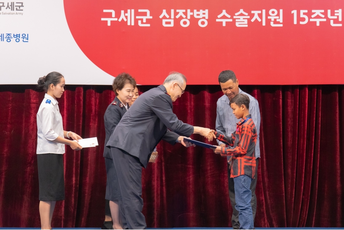 김병윤(왼쪽 세 번째) 사령관이 심장병 수술을 받은 B군에게 장학금 증서를 전달하고 있다. 왼쪽 두 번째는 차순삼 총재. 구세군 제공.