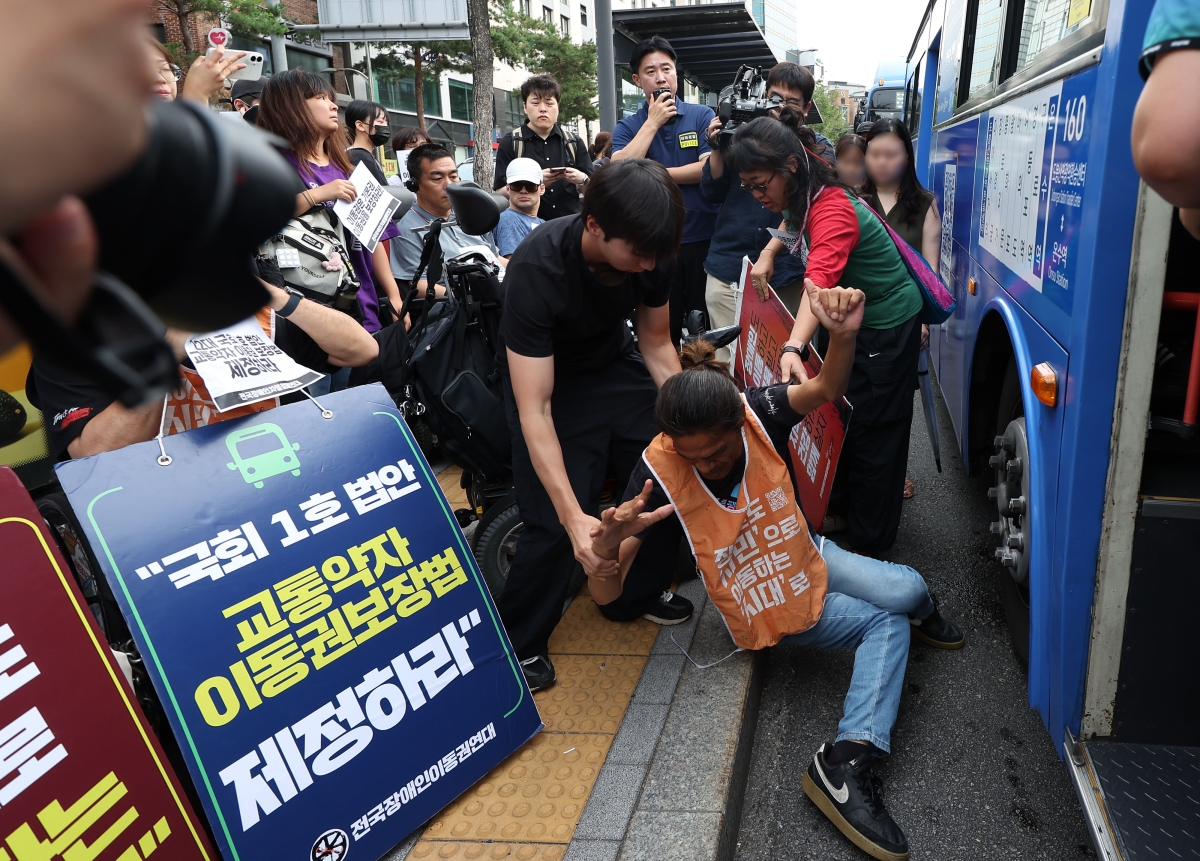 전국장애인차별철폐연대(전장연) 활동가들이 1일 서울 종로구 혜화동 버스정류장에서 버스 탑승을 시도하며 교통약자이동권보장법 전면 개정을 촉구하고 있다. 2026.7.1 뉴시스