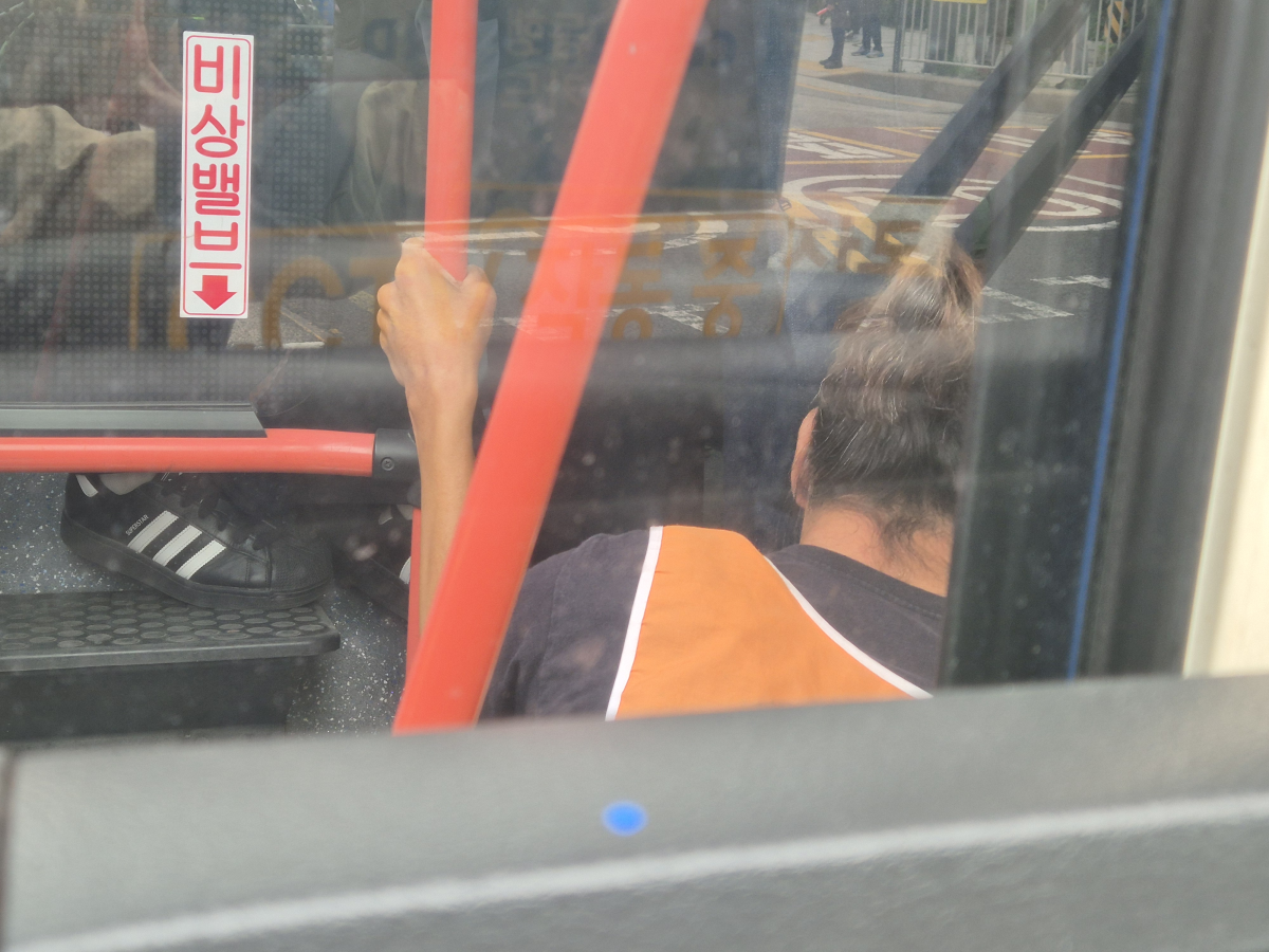 전장연 활동가가 휠체어에서 내려 맨몸으로 160번 시내버스 계단을 기어 오르고 있다. 반영윤 기자
