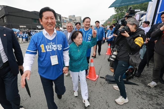 정청래 더불어민주당 총괄상임선거대책위원장이 21일 충남 공주산성시장에서 민주당 박수현 충남지사 후보와 김영빈 충남 공주부여청양 국회의원 보궐선거 후보 지원 유세를 하는 가운데 배우 전원주의 손을 잡고 이동하고 있다. 2026.5.21 연합뉴스