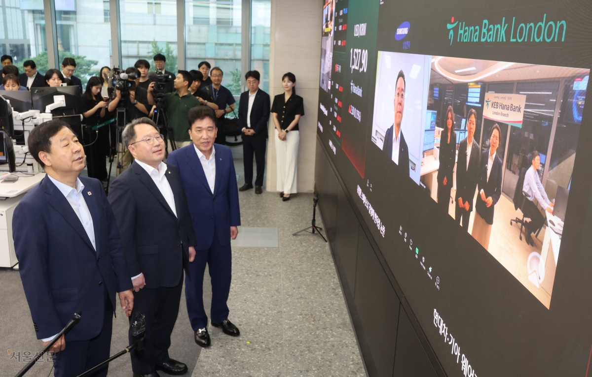구윤철(왼쪽부터) 부총리 겸 재정경제부 장관, 권민수 한국은행 부총재보, 함영주 하나금융그룹 회장이 24시간 외환시장이 개장한 6일 서울 중구 하나은행 딜링룸을 방문해 삼성전자 재경팀, 하나은행 런던지점 관계자들과 화상 대화를 하고 있다. 2026.7.6 이지훈 기자