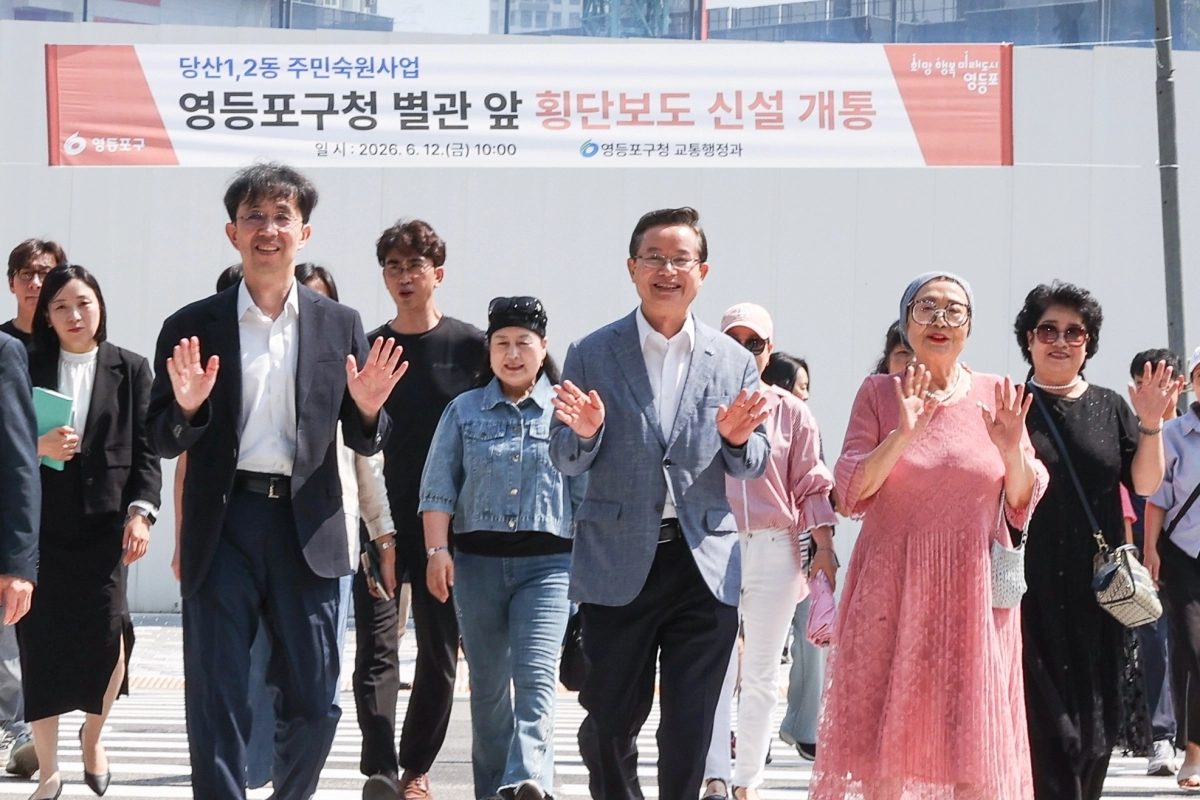 최호권(오른쪽 세 번째) 서울 영등포구청장과 당산동 주민들이 지난 12일 열린 구청 별관 앞 횡단보도 개통식에서 횡단보도를 함께 건너며 손을 흔들고 있다. 영등포구 제공