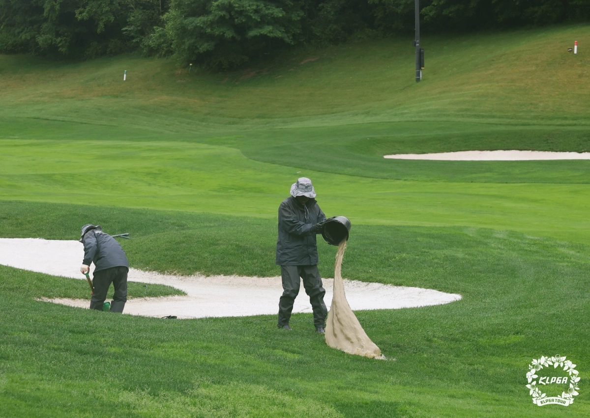경기 중 벙커에 고인 물을 퍼내는 대회 운영진. KLPGA 제공.