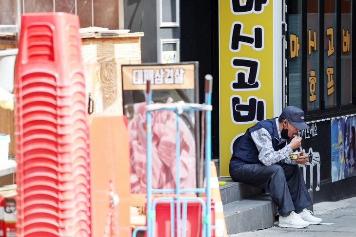 서울 종로구 탑골공원 인근 골목에서 한 어르신이 간편 죽으로 끼니를 때우고 있다.  뉴스1