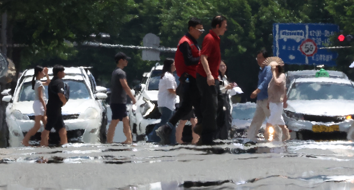대구에 폭염 경보가 발효된 11일 대구 중구 공평네거리에서 시민들이 지열로 인한 아지랑이가 피어오르는 도로 위를 지나가고 있다. 연합뉴스 2026.7.11