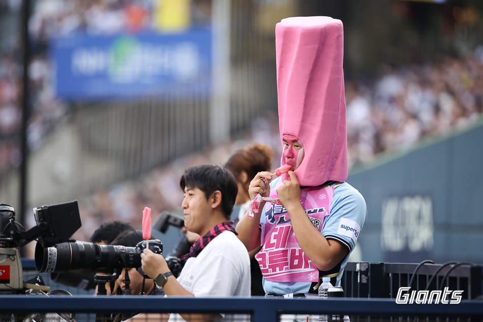 롯데 김진욱(오른쪽)이 11일 올스타전에서 스크류바 퍼포먼스를 펼친 뒤 카메라석에서 스크류바를 먹으며 경기를 지켜보고 있다.                            롯데 자이언츠 제공