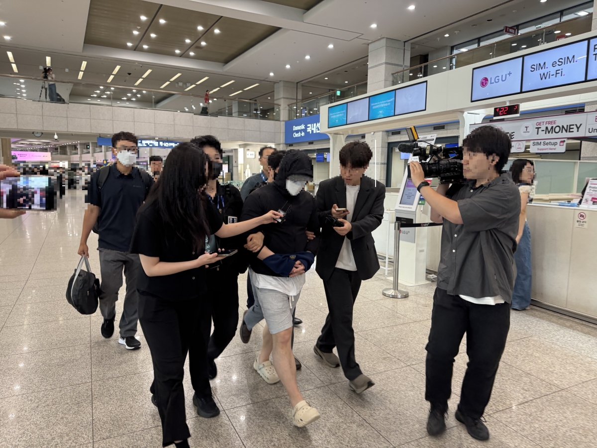 해외에서 판돈 5000억원대 불법 도박사이트를 운영하다 인터폴에 체포된 40대 피의자가 인천국제공항에서 체포영장이 집행된 후 경찰에 의해 이송되고 있다. [경기북부경찰청 제공]