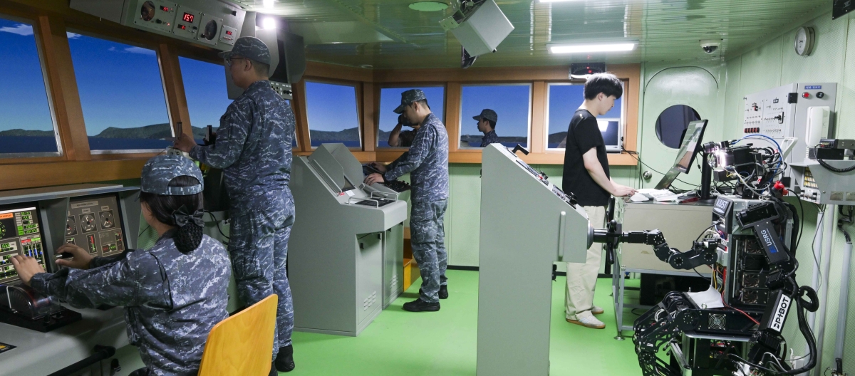 지난 23일 해군교육사령부 조함훈련장에서 해군 최초로 진행된 로봇 승조원 전투실험에서 휴머노이드 로봇 ‘파이봇(PIBOT)’이 이지스구축함 서애류성룡함(DDG) 소속 함교 당직사관의 조함명령에 따라 타수 업무를 수행하고 있다. 해군 제공