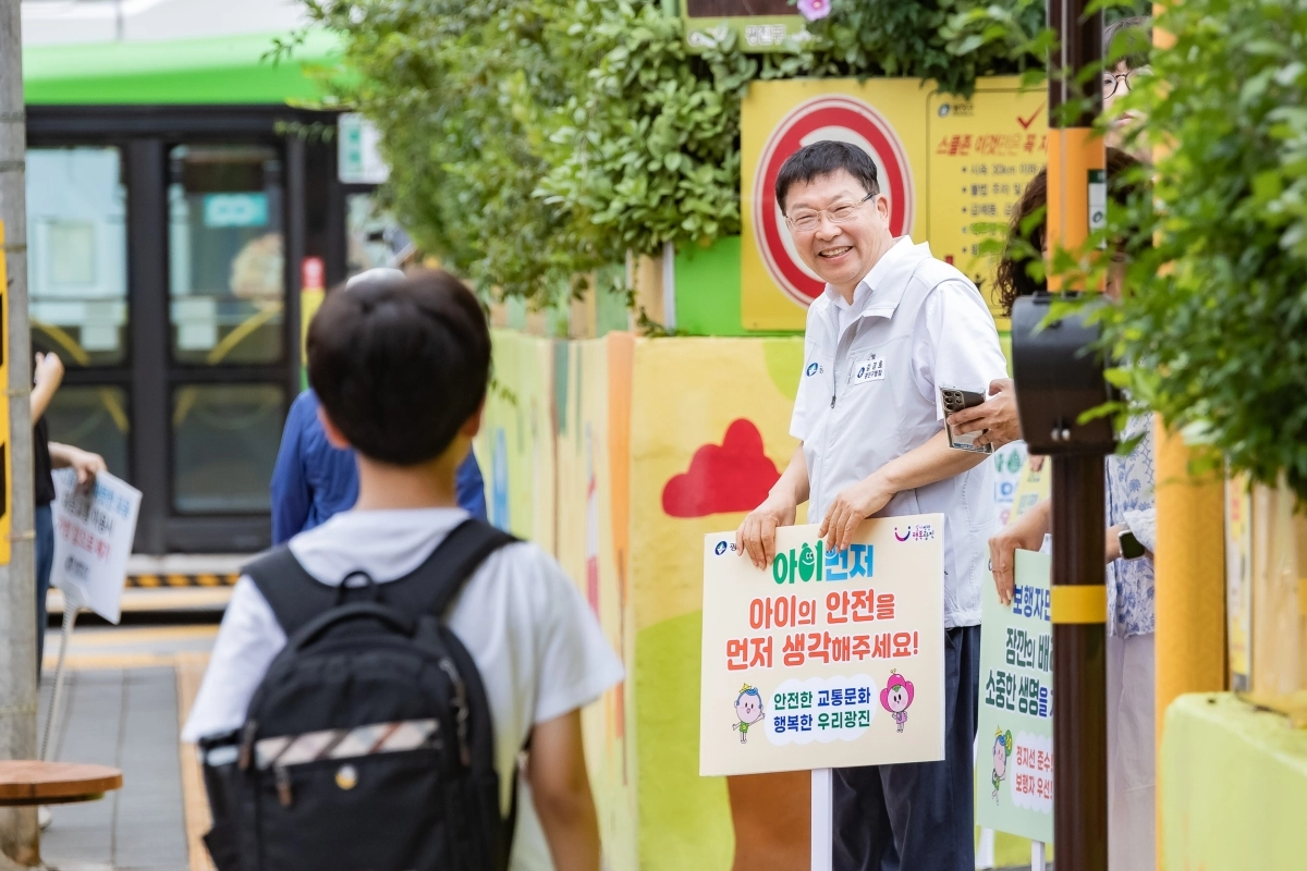 김경호 서울 광진구청장이 지난 22일 광진구 자양동 성자초 앞에서 ‘아이의 안전을 먼저 생각해 주세요’라고 적힌 팻말을 들고 어린이를 바라보며 웃고 있다. 광진구 제공