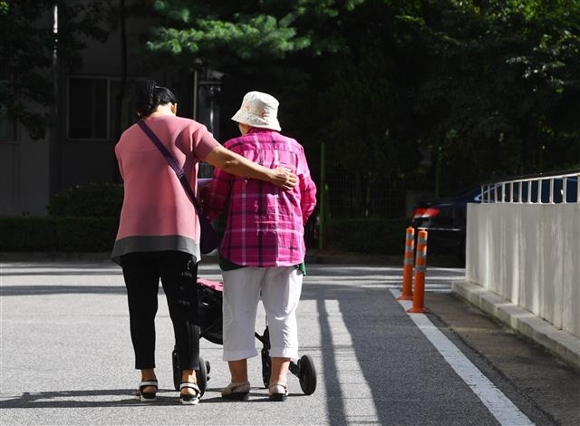 몸이 불편한 노인을 부축하고 있는 여성 요양보호사의 뒷모습. 서울신문 DB