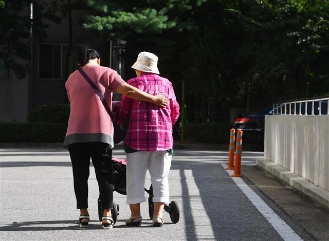 몸이 불편한 노인을 부축하고 있는 여성 요양보호사의 뒷모습. 서울신문 DB