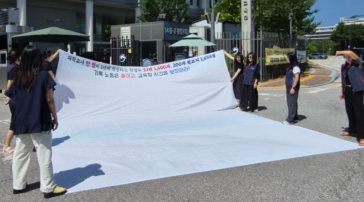교사노동조합연맹이 31일 정부세종청사 교육부 앞에서 기자회견을 열고 학교생활기록부(학생부) 제도 전면 개편을 촉구하며 현수막 퍼포먼스를 하고 있다. 교사노조 제공