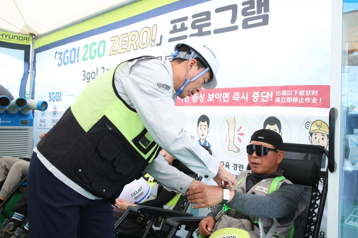 신재점(왼쪽) 현대건설 CSO가 최근 인천 서구 가좌테크센터 현장에서 ‘H-체온밴드’를 통해 근로자 건강 상태를 체크하고 있다.  현대건설 제공