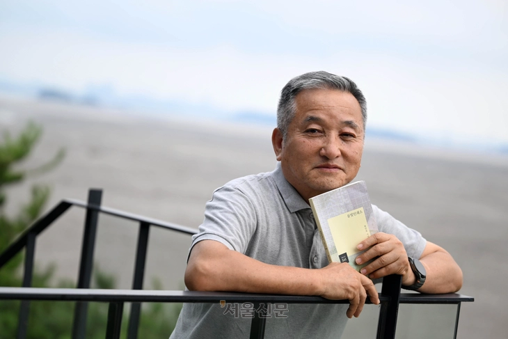 지난달 31일 인천 강화군에서 만난 함민복 시인은 “우리는 모두 질문의 중독자가 돼야 한다”고 강조했다. 이번 시집 ‘물빛인쇄소’를 손에 든 시인의 뒤로 강화 동막해수욕장의 갯벌이 넓게 펼쳐져 있다. 홍윤기 기자