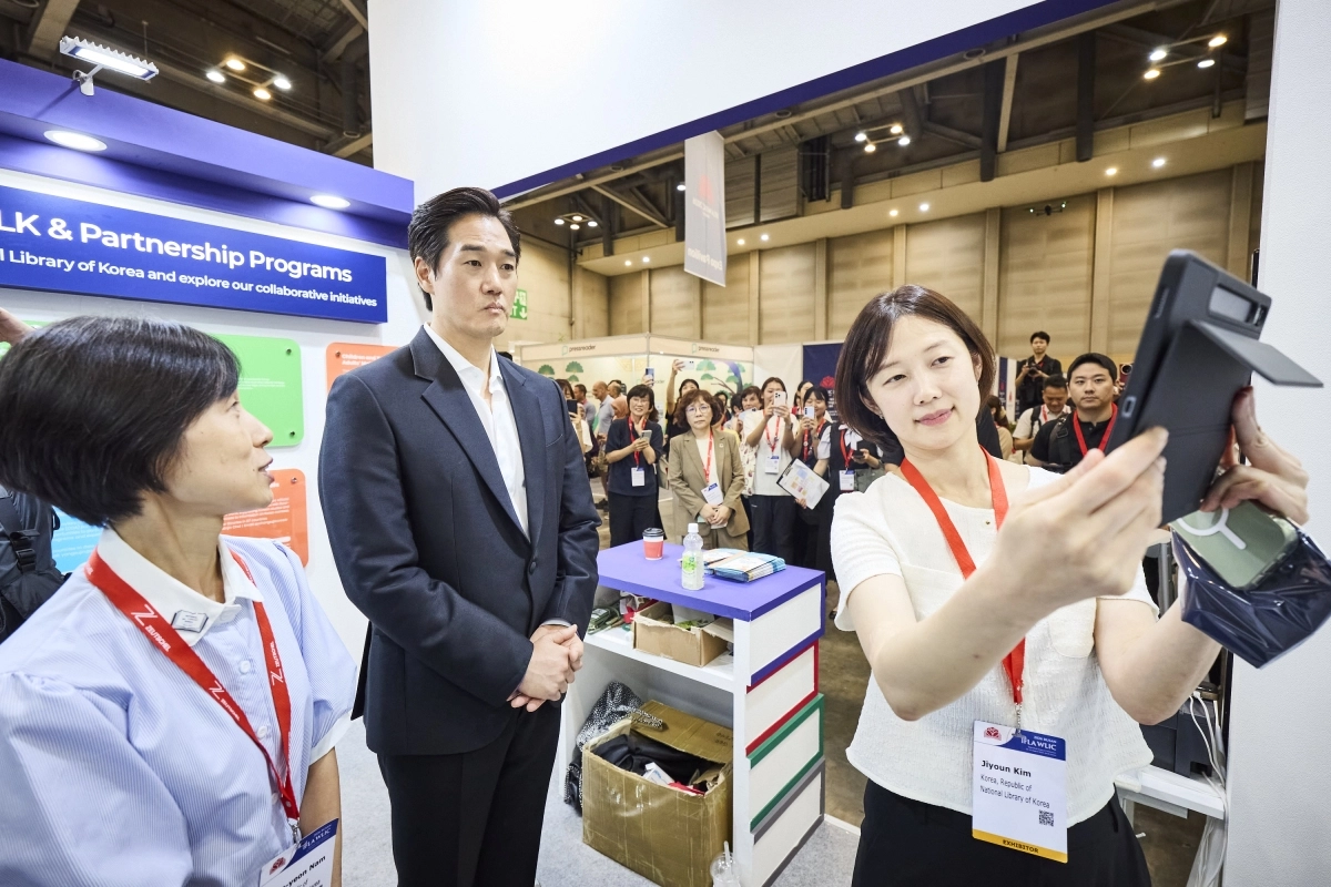 ▲배우 유지태가 전시 부스를 방문해 관계자의 설명을 들으며 디지털 콘텐츠를 살펴보고 있다. (사진제공=2026 부산 WLIC 국가위원회)