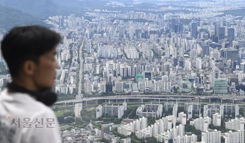 정부의 부동산 세제 개편안을 둘러싼 논란과 후폭풍이 계속되고 있는 가운데 12일 서울 송파구 롯데월드타워 서울스카이에서 한 시민이 아파트 단지를 바라보고 있다. 이지훈 기자