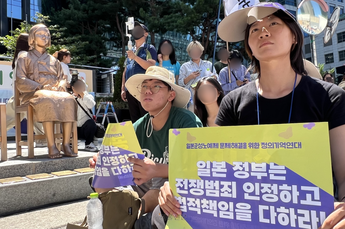 시민들이 12일 서울 종로구 주한일본대사관 앞에서 열린 일본군 위안부 피해자 기림의 날 맞이 세계연대집회에 참석해 일본 정부가 전쟁 범죄를 인정하고 법적 책임을 질 것을 촉구하는 내용의 피켓을 들고 있다.
