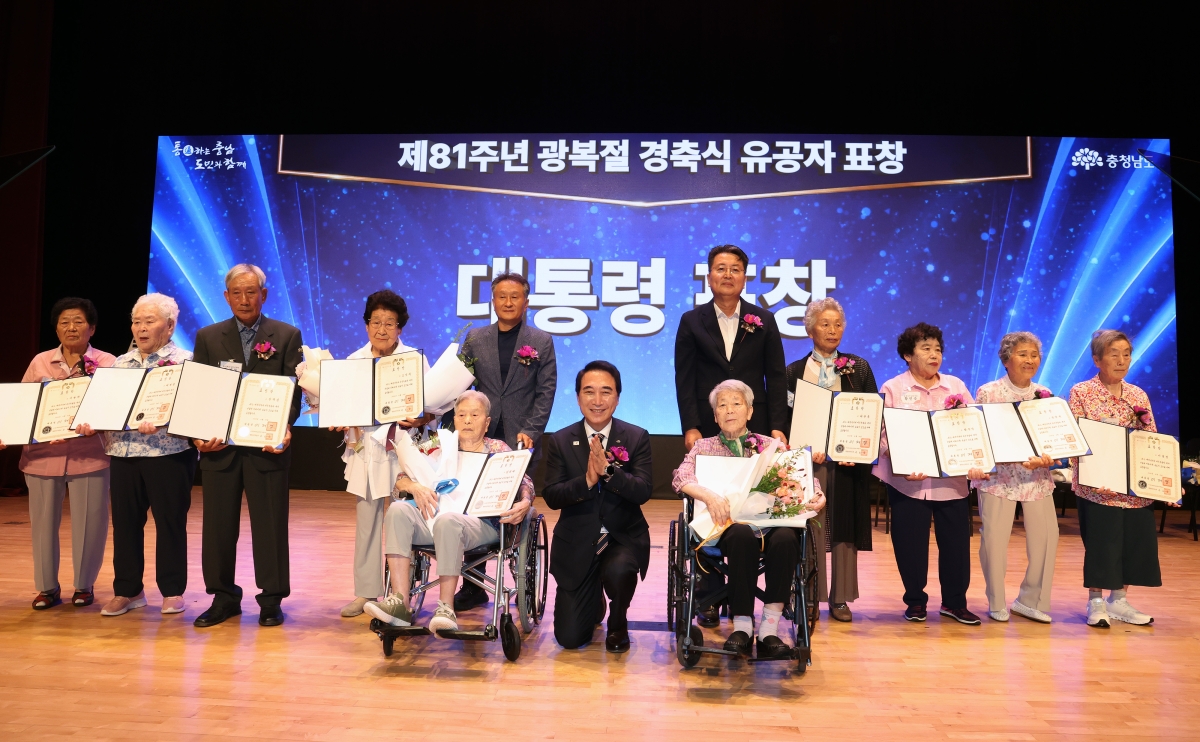 박수현 충남도지사가 제81주년 광복절 경축식 유공자 표창식에서 유공자들 옆에 한쪽 무릎을 꿇고 기념촬영을 하고 있다. 도 제공