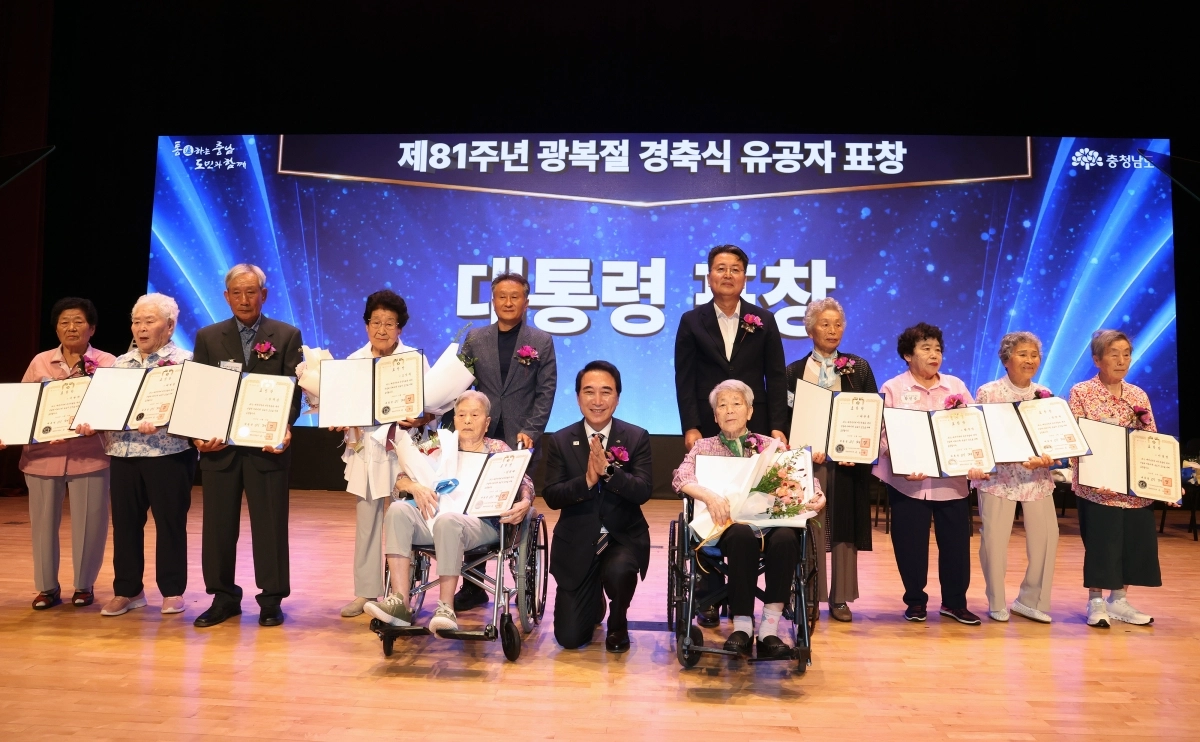 박수현 충남도지사가 제81주년 광복절 경축식 유공자 표창식에서 유공자들 옆에 한쪽 무릎을 꿇고 기념촬영을 하고 있다. 도 제공