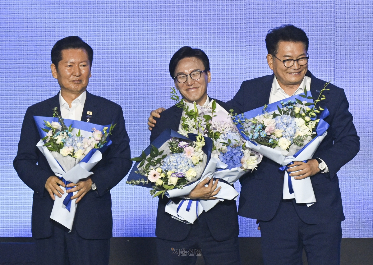 신임 더불어민주당 대표로 선출된 김민석(가운데) 당선인이 17일 대전 유성구 대전컨벤션센터 제2전시장에서 열린 제3차 더불어민주당 정기전국당원대회(전당대회)에서 꽃다발을 든 채 송영길 후보에게 축하받고 있다. 왼쪽부터 정청래 후보, 김 당선인, 송영길 후보. 2026.8.17 대전 이지훈 기자