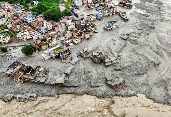 A drone view shows mud covering properties following a flash flood in Trishuli