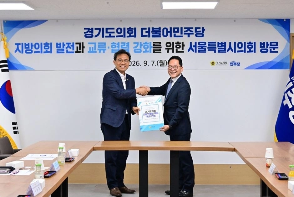 이상훈 서울시의회 대표의원(왼쪽)과 안광률 경기도의회 대표의원이 악수하며 기념촬영을 하고 있다. 서울시의회 제공