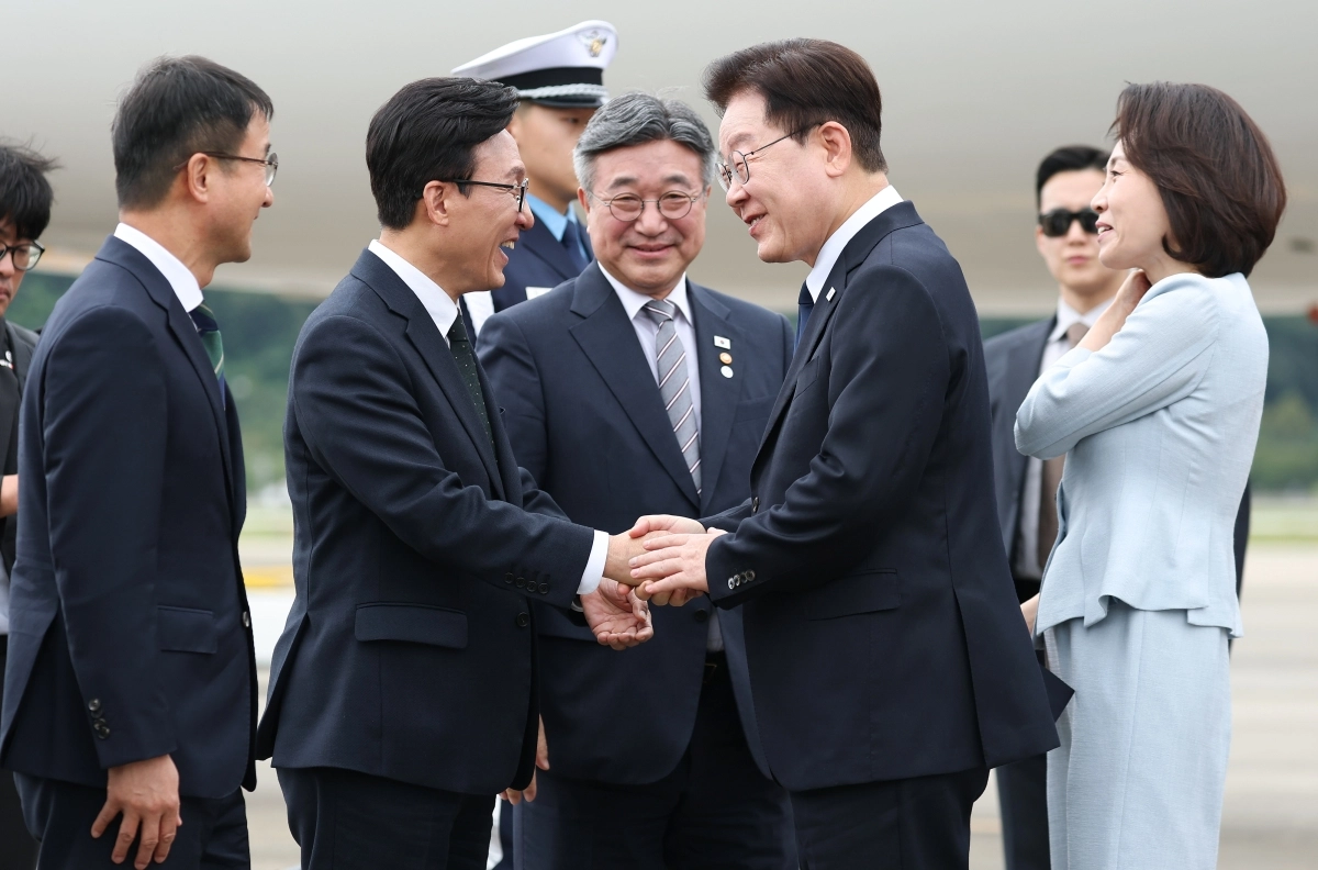 프랑스 국빈 방문 일정을 마치고 귀국한 이재명 대통령이 10일 서울공항에 환영 나온 김민석 더불어민주당 대표와 활짝 웃으며 악수하고 있다. 왼쪽부터 한병도 민주당 원내대표, 김 대표, 윤호중 행정안전부 장관, 이 대통령, 김혜경 여사. 뉴스1