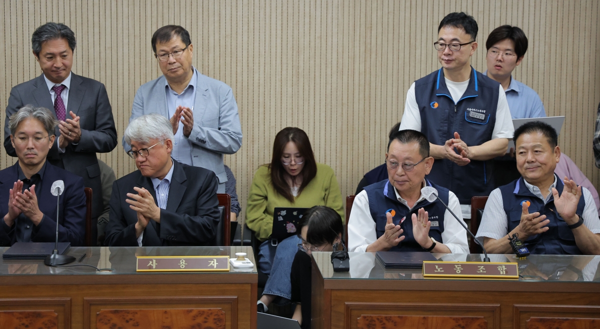 김정환(앞줄 왼쪽 두번째) 서울시 버스운송조합 이사장과 박점곤(왼쪽 세번째) 서울시버스노동조합 위원장이 16일 서울 영등포구 서울지방노동위원회에서 2026년 임금 협약을 담은 조정안에 서명한 뒤 박수를 치고 있다. 연합뉴스