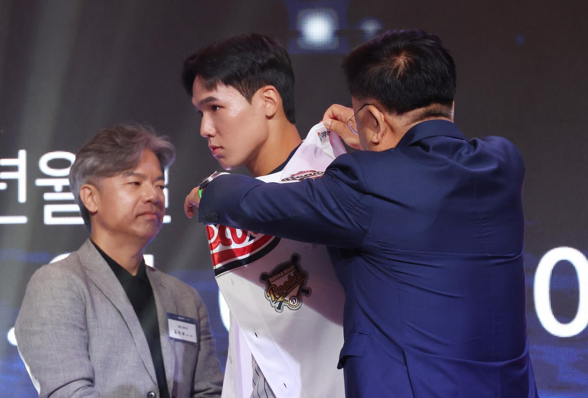 21일 서울 롯데호텔 월드에서 열린 2027 KBO 신인 드래프트에서 1라운드 2순위로 두산 베어스 지명을 받은 서울고 김지우가 유니폼을 받아 입고 있다.    연합뉴스