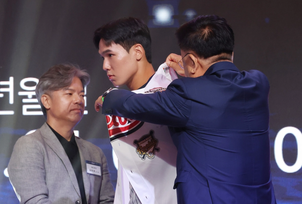 21일 서울 롯데호텔 월드에서 열린 2027 KBO 신인 드래프트에서 1라운드 2순위로 두산 베어스 지명을 받은 서울고 김지우가 유니폼을 받아 입고 있다.    연합뉴스