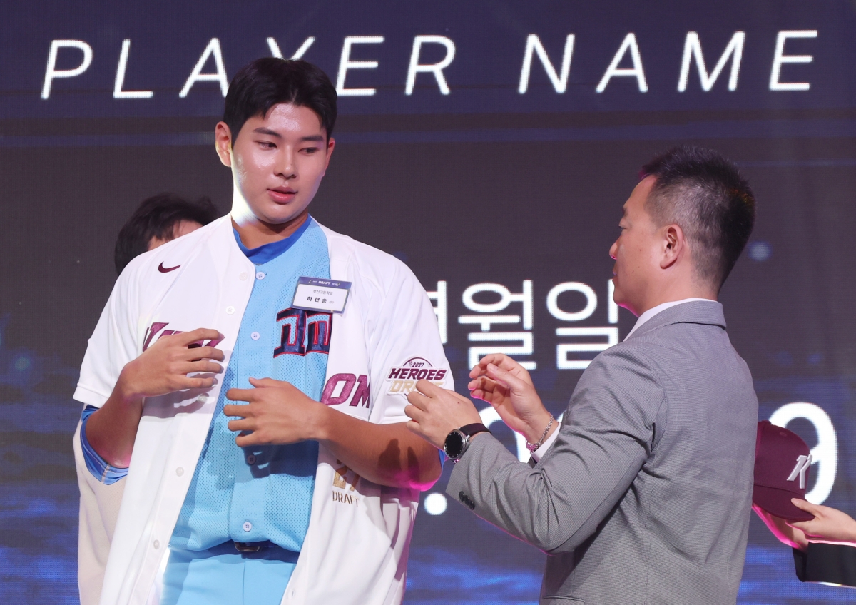 21일 서울 롯데호텔 월드에서 열린 2027 KBO 신인 드래프트에서 전체 1순위로 키움 히어로즈의 지명을 받은 부산고 하현승이 유니폼을 받아 입고 있다.   연합뉴스