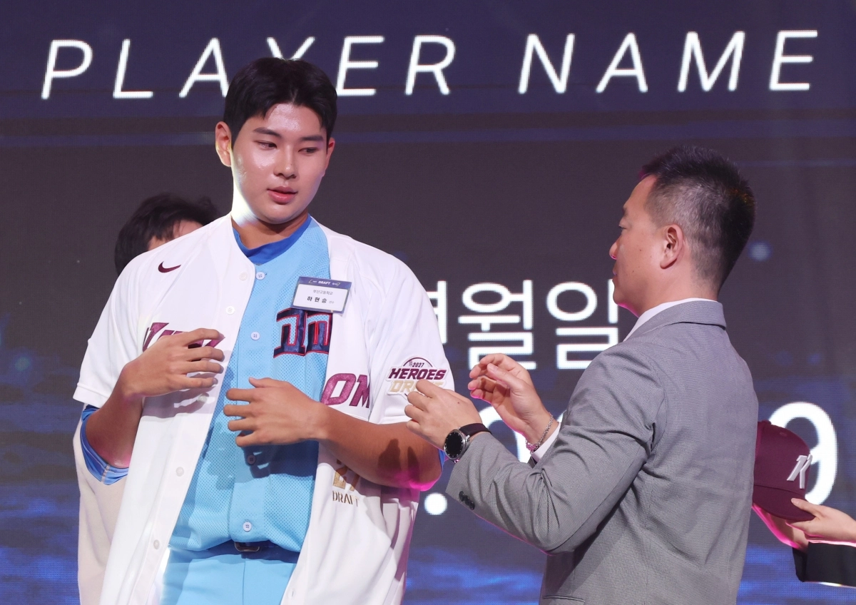 21일 서울 롯데호텔 월드에서 열린 2027 KBO 신인 드래프트에서 전체 1순위로 키움 히어로즈의 지명을 받은 부산고 하현승이 유니폼을 받아 입고 있다.   연합뉴스