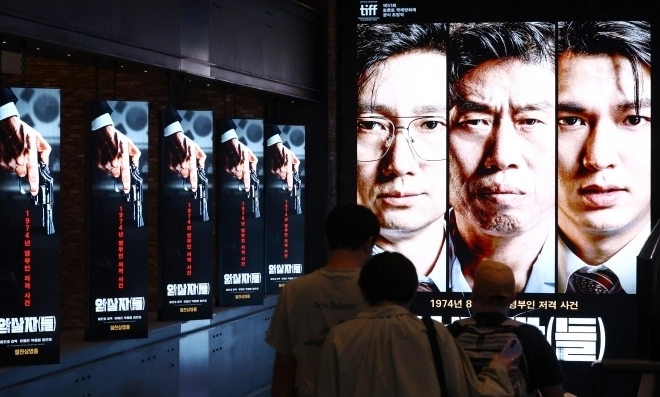 육영수 여사 피격 사건을 다룬 영화 ‘암살자(들)’을 둘러싼 논란이 확산하는 가운데 28일 서울의 한 영화관에 걸린 ‘암살자(들)’ 홍보물. 2026.9.28 연합뉴스
