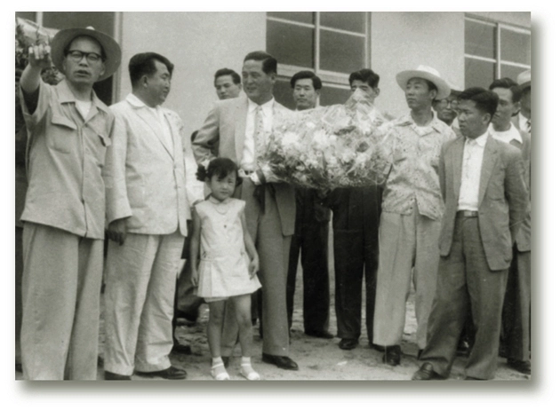 김종희(가운데) 한화그룹 창업주가 1952년 조선화약공판을 인수한 뒤 축하하는 직원들의 꽃다발을 받고 있다. 한화그룹 제공