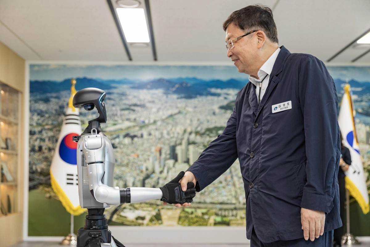 김경호(오른쪽) 서울 광진구청장이 지난 달 청사 내 오픈스페이스에서 휴머노이드 로봇과 악수하며 웃고 있다.  광진구 제공