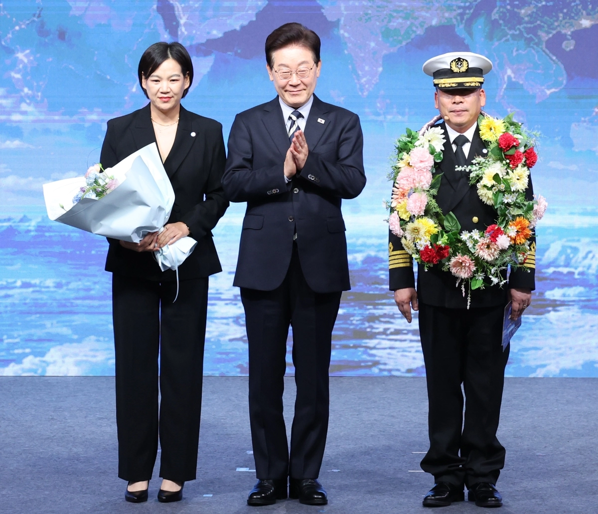 이재명 대통령이 13일 부산에서 열린 북극항로 시범운항 환영식에서 팬스타 아크로호 서명원 선장에게 꽃목걸이를 전달한 후 가족과 기념촬영을 하고 있다. 2026.10.13 부산 연합뉴스
