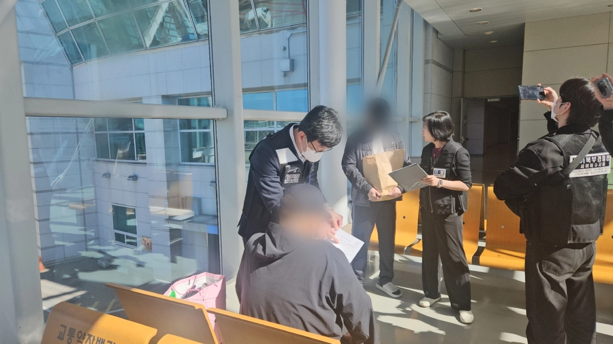 2조 6000억원 규모의 불법 도박사이트 운영에 관여한 부총책 B씨(앉아 있는 사람)와 별도의 5000억원대 불법 도박 사이트 개발자 C씨(서 있는 사람)가 14일 인천국제공항을 통해 국내로 송환됐다. 사진은 경찰이 영장을 집행하는 모습. 경찰청 제공
