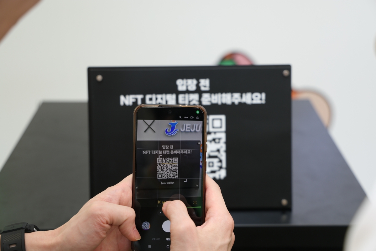 16일 제주 서귀포시 제주월드컵경기장에서 관람객이 휴대전화에 표시된 대체불가능토큰(NFT) 티켓의 QR코드를 입장 확인 장치에 갖다 대고 있다. 네이버페이 제공
