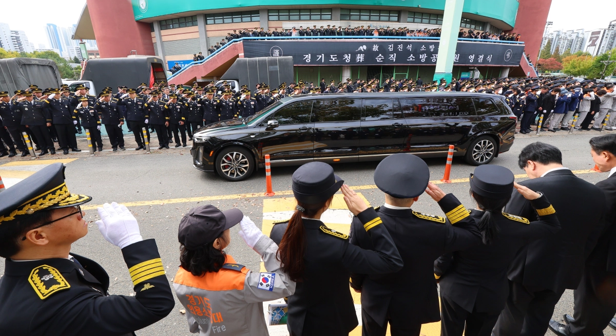 19일 경기 부천시 원미구 부천체육관에서 열린 김진석 소방위의 영결식이 끝난 뒤 떠나는 운구 차량을 향해 동료 소방대원들이 거수경례를 하고 있다. 연합뉴스