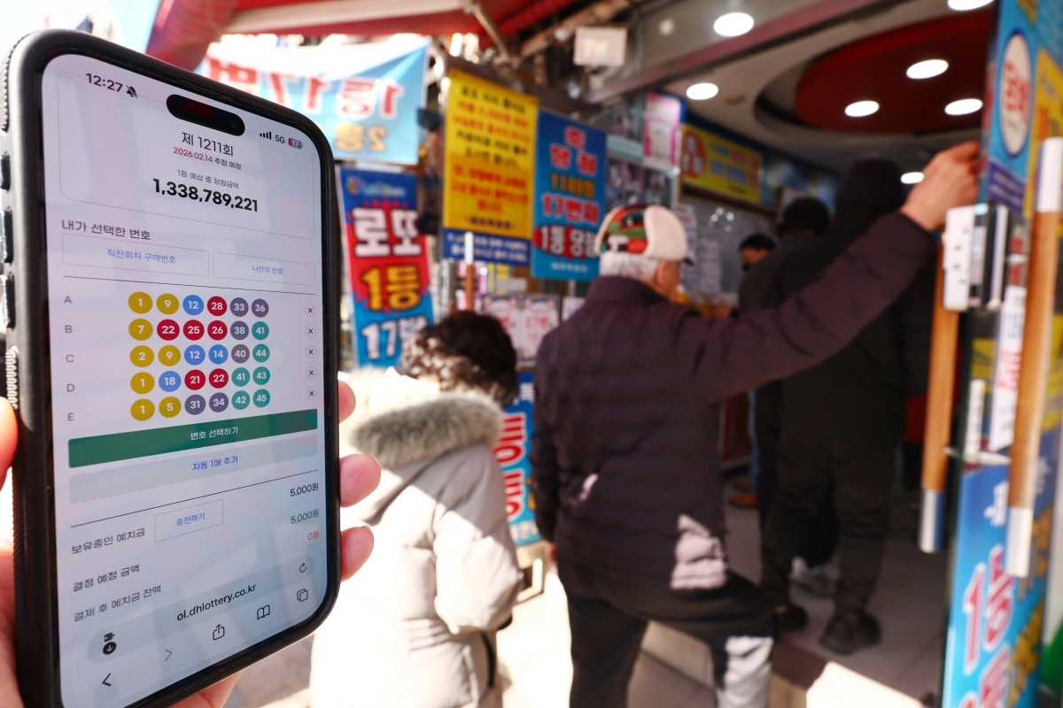 지난 2월 9일 서울 시내 한 복권 판매점 앞에서 휴대폰 화면에 나오는 로또 모바일 판매 페이지 뒤로 시민들이 로또를 구매하고 있다. 뉴시스